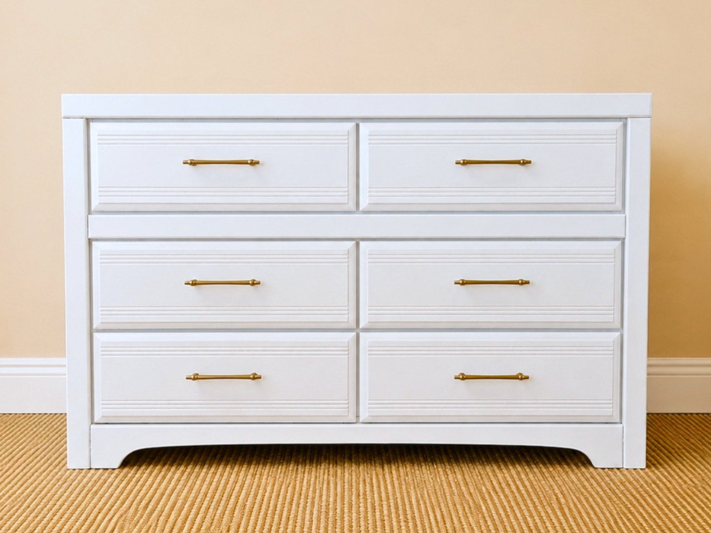 Refinished cream white six-drawer dresser with champagne gold hardware styled in a bright, neutral bedroom with blush accents.