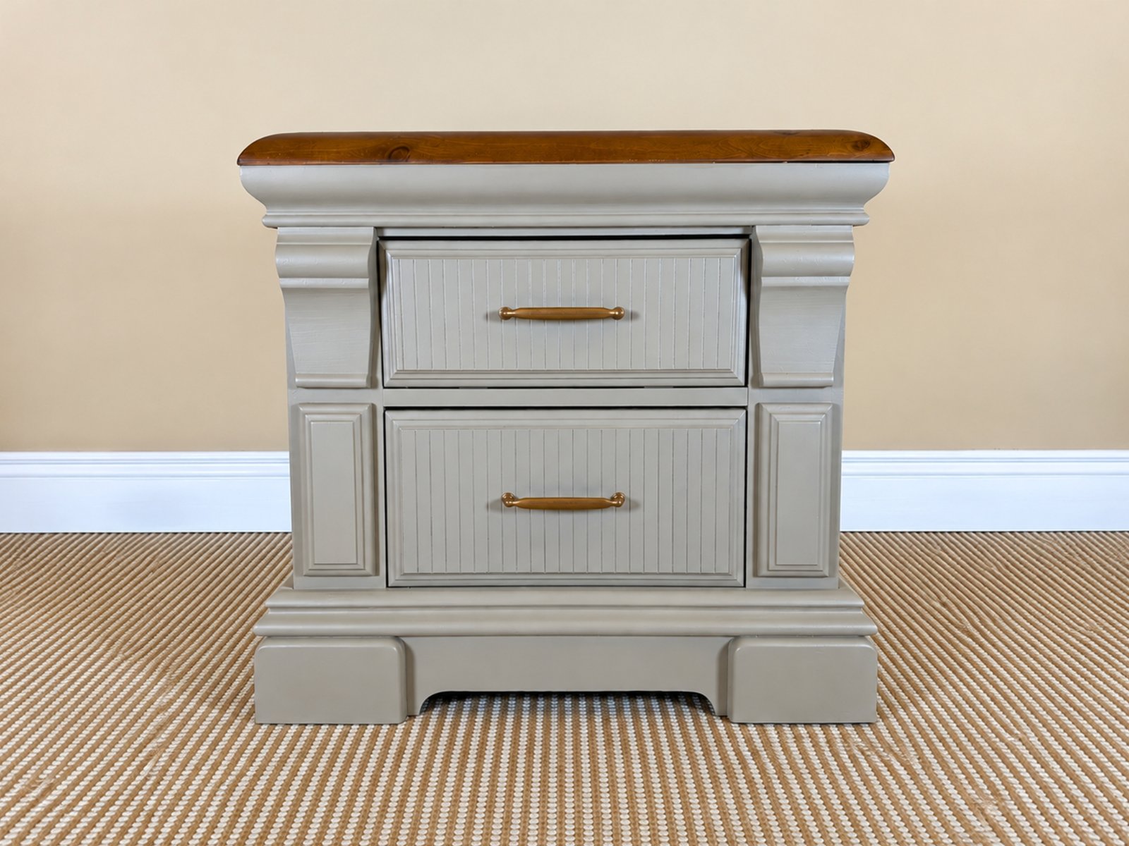 Sandstone two-drawer nightstand with stained wood top and antique brass hardware